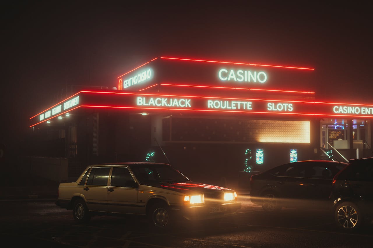 Dubibet Entry | Official Login & Fast Access Platform Vintage cars parked outside a neon-lit casino at night, showcasing urban nightlife.