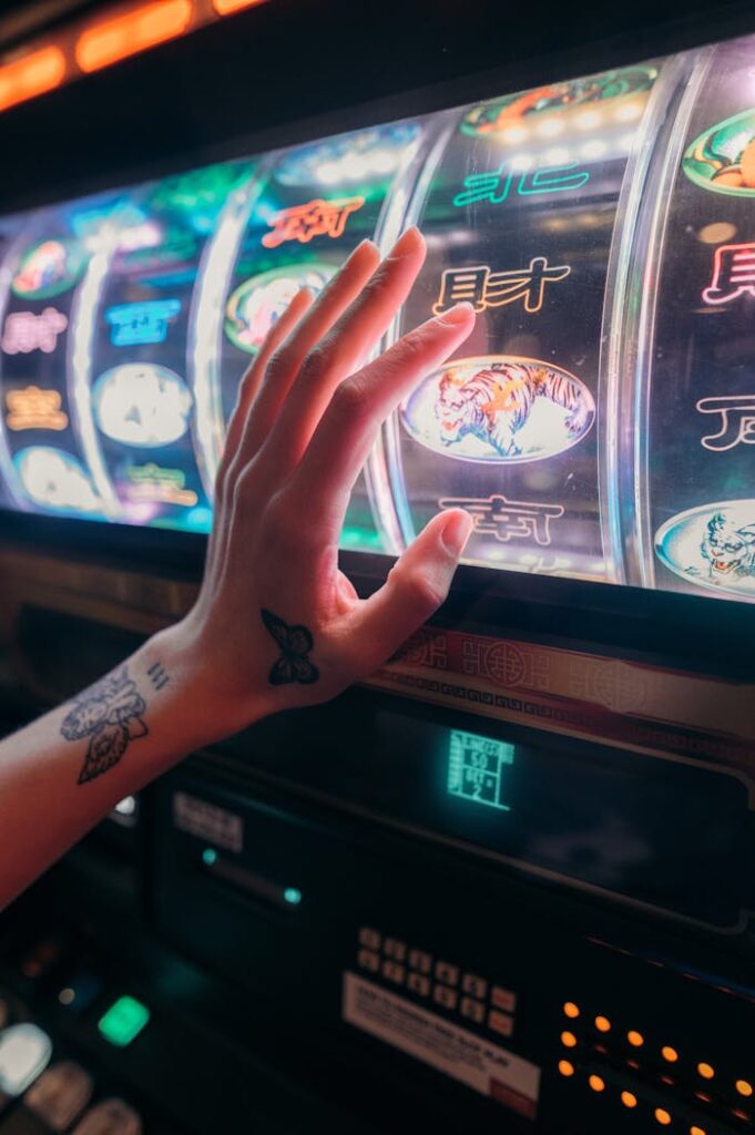 Dubibet Secure Access Tattooed hand playing slot machine in vibrant casino setting, emphasizing chance and excitement.