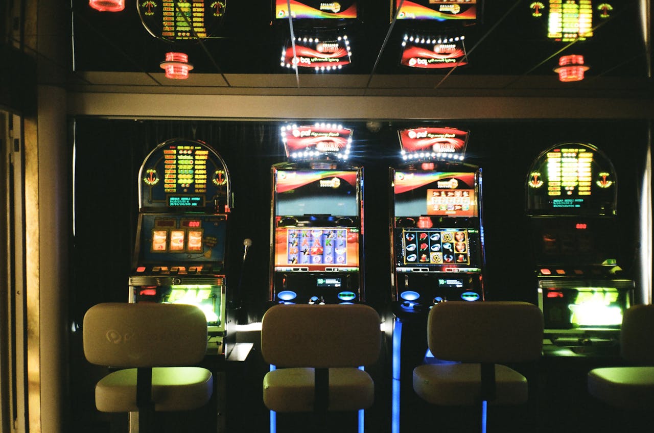 Dubibet Access Link | Secure Login for Casino Players. Slot machines in a dimly lit casino with reflective ceiling and empty chairs.