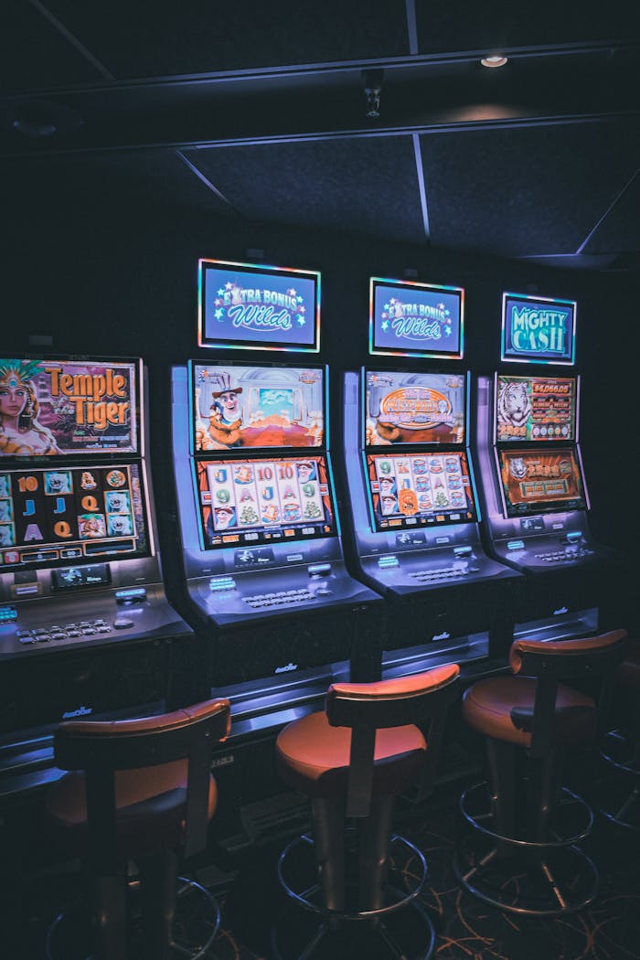 Dubibet Login – Secure Access to the Official Betting Site. Row of illuminated slot machines in a dimly lit, empty casino area.