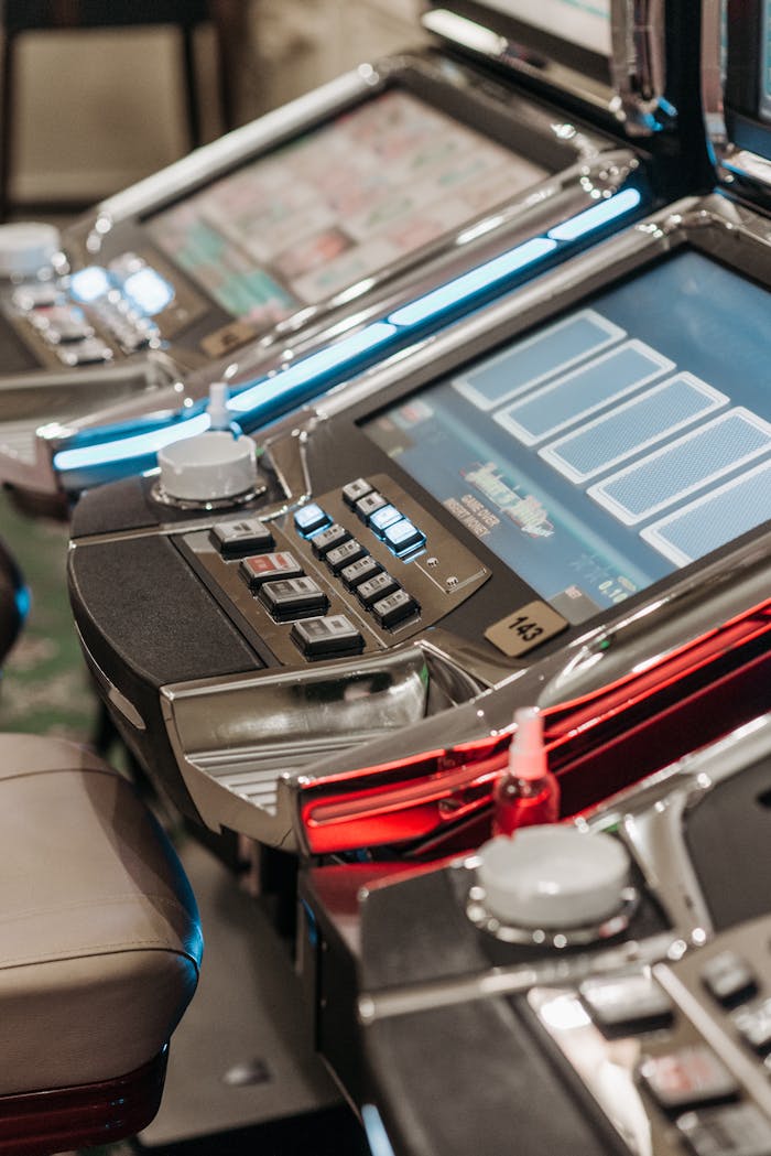 Dubibet Entry Link | Safe Login and Member Access. Detailed view of illuminated slot machines in a casino, showcasing vibrant screens and controls.