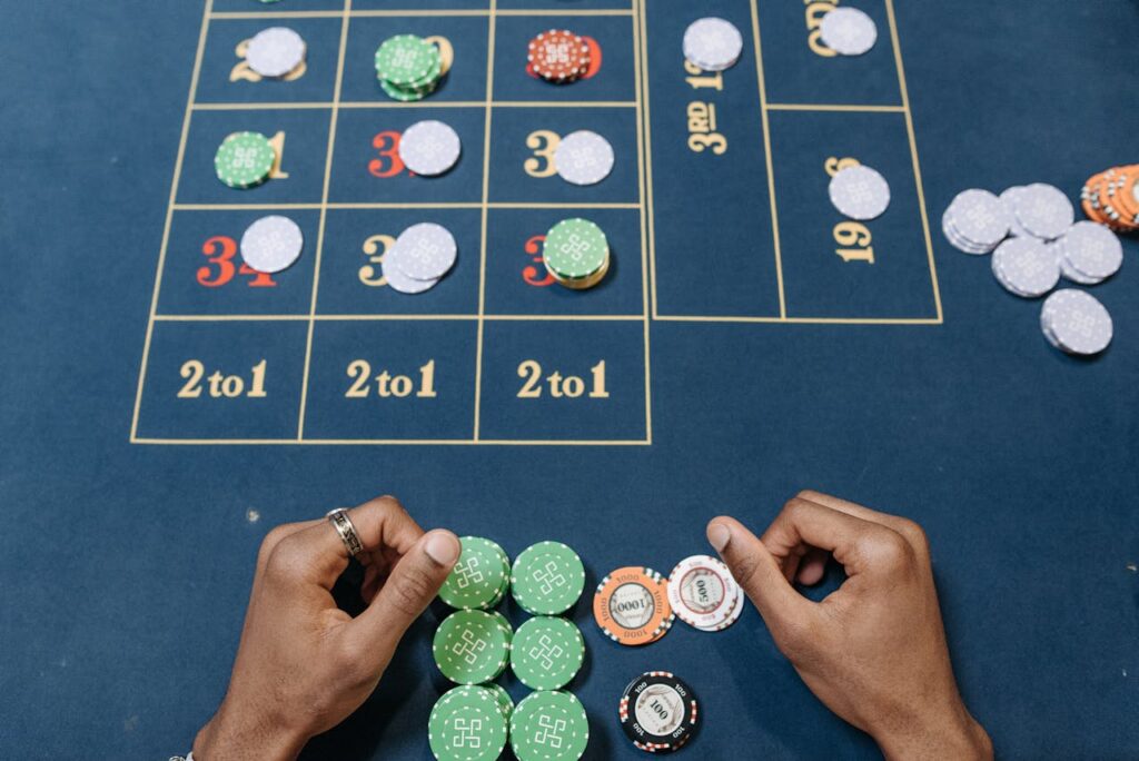 Dubibet Account Login | Entry & Fast Register Options Hands arranging poker chips on a colorful casino gaming table, top view.